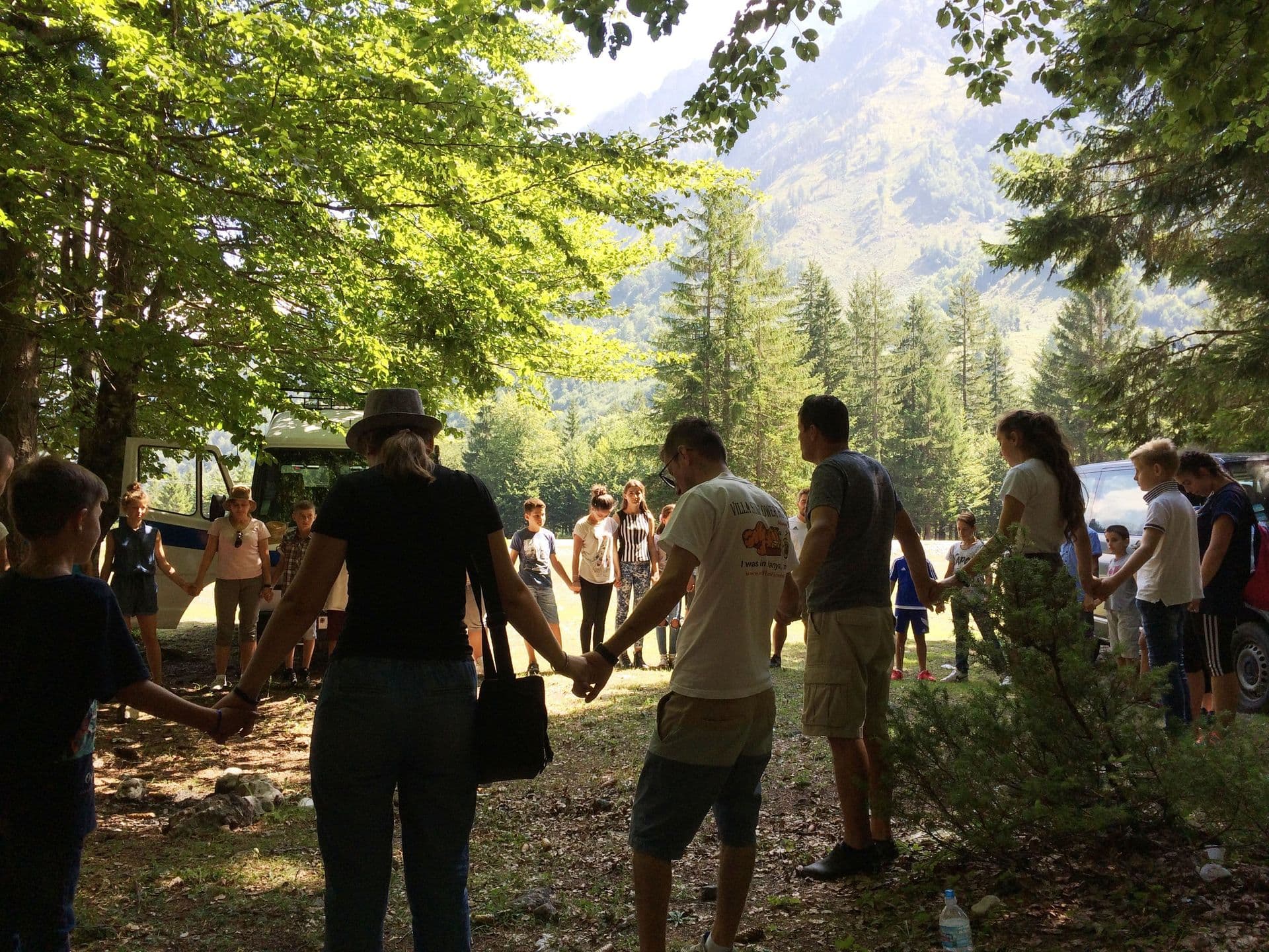 The participants of Journey to the North (a travelling discipleship ministry) along with members of a local church and local kids praying during a one-day kids' event in mountainous northern Albania.