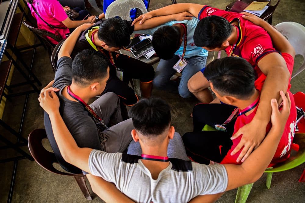 A group of guys praying before teens start to arrive at TeenStreet KK.
