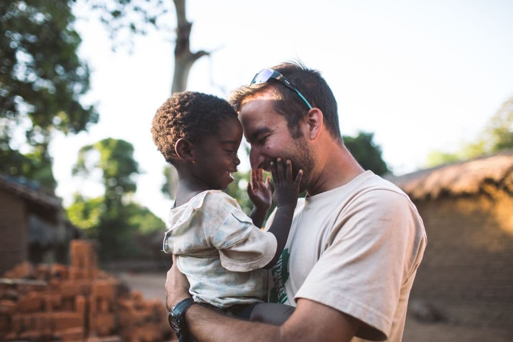 afbeelding man met kind Ghana omhelzing na delen goed nieuws evangelie zending missiewerker